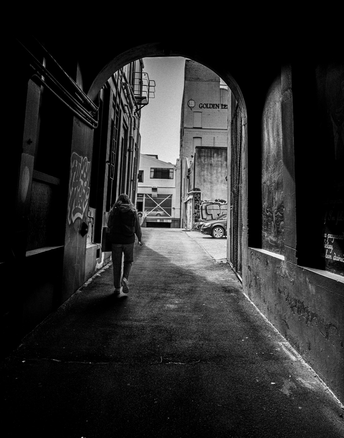 Figure walking through an alley, black and white