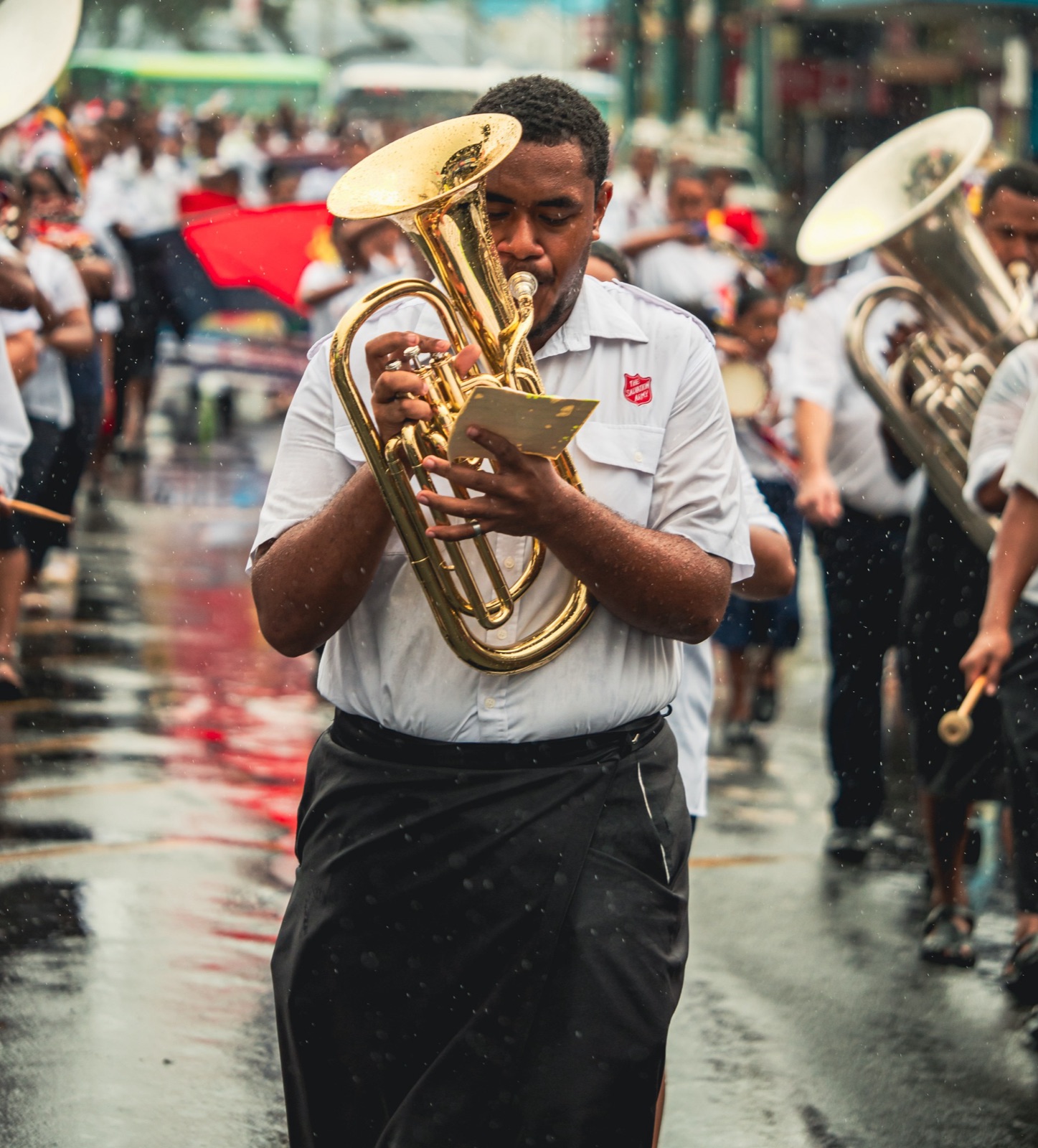 Brass band musician playing in the rain during a parade