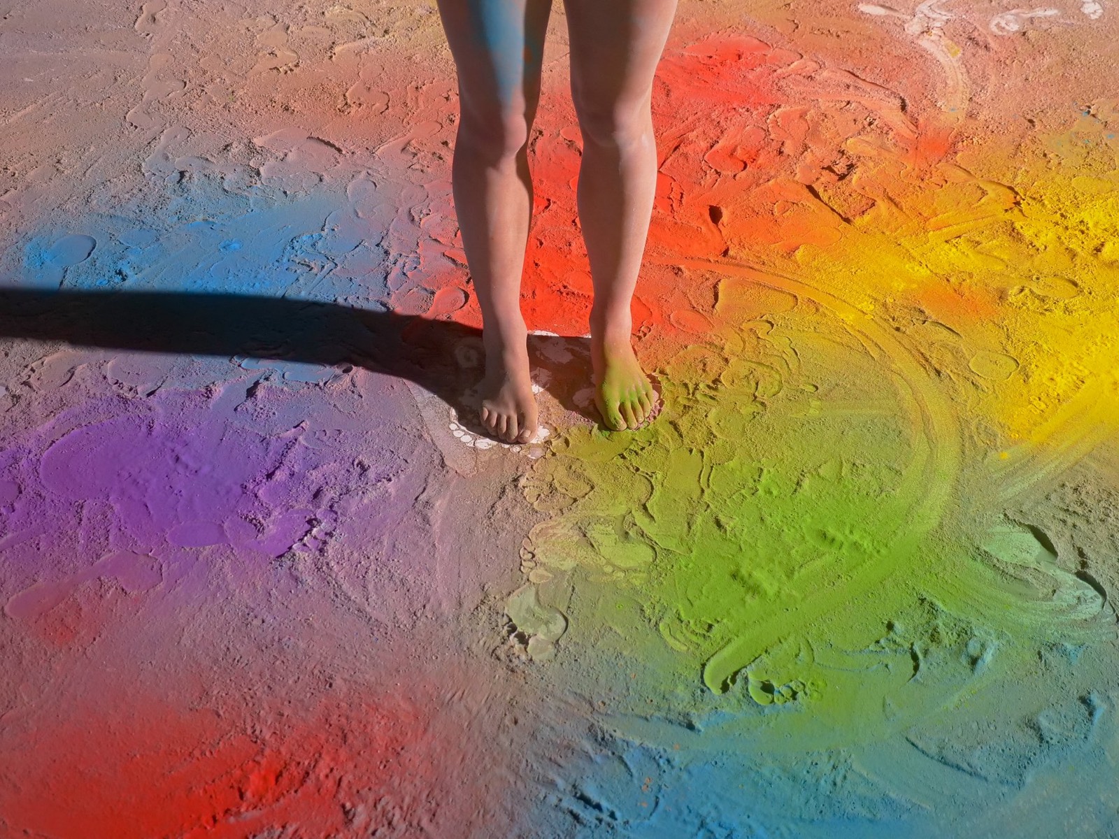 Bare feet on a floor covered in coloured pigment